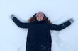 © Евгений Шемякин - Happy positive girl, young beautiful woman is lying in the white snow, having fun at winter cold frosty day