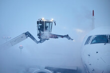 Deicing Of Airplane Before Flight. Winter Day At Airport During Snowfall..