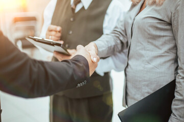 Wall Mural - close up. businesswoman shaking hands with a business partner. handshake at sunset with a sun glare