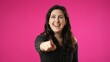 © Robert Peak - Portrait of smiling laughing beautiful brunette young woman 20s 30s years old pointing finger posing isolated on pink background studio. People sincere emotions lifestyle concept.