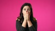 © Robert Peak - Shocked worried scared brunette young woman 20s posing isolated on pink background studio. People lifestyle concept. Covering mouth eyes with hands hiding