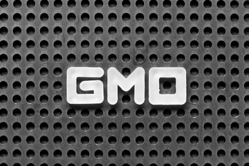 Sticker - White alphabet letter in word GMO (abbreviation of Genetically Modified Organisms) on black pegboard background