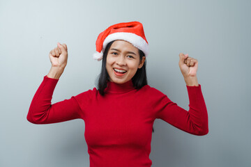 Pretty lovely lady asian thai women in red sweater and santa christmas hat isolated over grey background. dancing