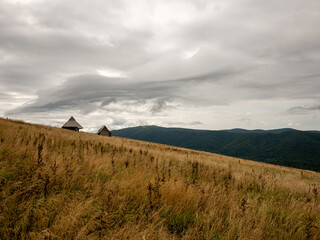 landscape in the mountains with two huts on the hill slope