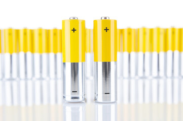 Alkaline AA batteries close up and blurry batteries group on white background