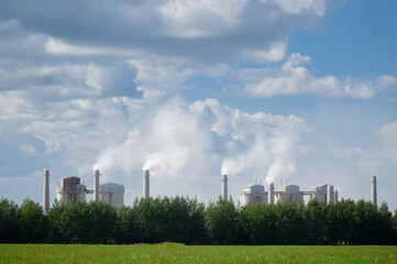 Tall chimneys of a factory with smoke rising up, polluting the atmosphere. Air pollution concept.