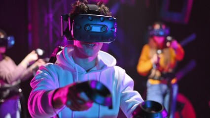 Wall Mural - A joyful, interested boy is playing on VR treadmill with helmet, controllers and a backpack. Other people playing nearby. Slow motion