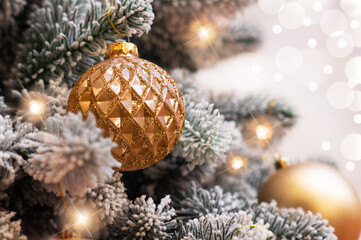 The Christmas tree is decorated with beautiful golden balls on a shiny sparkling background with beautiful bokeh. Christmas background.