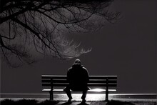  A Person Sitting On A Bench In The Dark With A Tree In The Background And A Light Shining On The Ground.