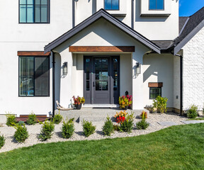 Front view close up shot of a big white beautiful luxury two garage home with luscious green grass  on a blue sky day in the suburbs.