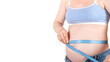 big belly young pregnant overweight woman no face in blue jeans and top, holding measurement sewing tape, flexible ruler, isolated on white background. estimating growing size with device, banner
