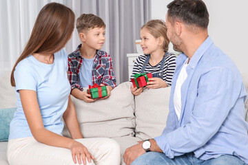 Canvas Print - Little children presenting their parents with gifts at home