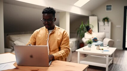 African american man working at home with laptop on a wooden desk at home
