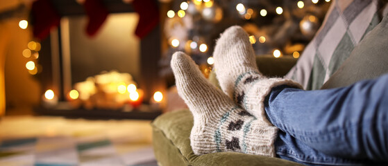 Canvas Print - Young woman in warm socks lying on sofa at home on Christmas eve, closeup