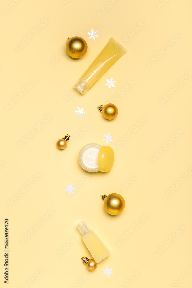 Composition with cosmetic products and Christmas decorations on yellow background