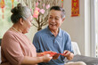 Joyful senior couple discussing lucky money envelopes they prepared for Tet celebration