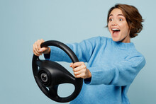Side View Young Excited Cheerful Fun Woman In Knitted Sweater Look Camera Hold Steering Wheel Driving Car Isolated On Plain Pastel Light Blue Cyan Background Studio Portrait People Lifestyle Concept
