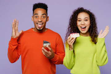 Young exultant happy cheerful couple two friends family man woman of African American ethnicity wear casual clothes together hold donut spread hands isolated on pastel plain light purple background.