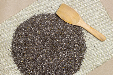 Wall Mural - Healthy food, Chia seeds with wooden spoon in linen cloth over cardboard texture background