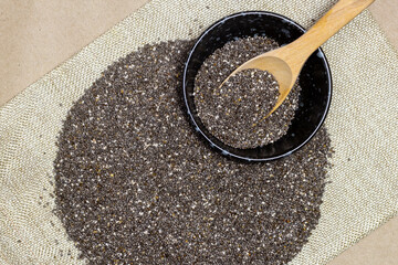 Wall Mural - Healthy breakfast, Chia seeds with wooden spoon in black bowl and superfood heap on linen cloth