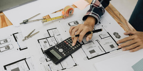 Concept architects, engineer holding pen pointing equipment architects On the desk with a blueprint in the office.