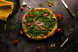 Flat lay photography, pizza with arugula and tomatoes on a black background