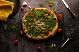 Fototapeta Niebo - Flat lay photography, pizza with arugula and tomatoes on a black background