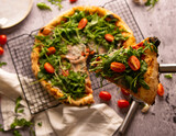 Fototapeta Niebo - Flat lay photography, pizza with arugula and tomatoes on laid on a tray with one of the pieces cut out