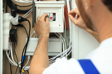 Canvas Print - Electrician switching off circuit breakers in fuse box, closeup