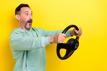 Poster - Photo of impressed astonished guy dressed mint sweatshirt hold steering wheel look empty space isolated on yellow color background