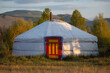 Nomadic persons yurt in rural Mongolian landscape. Ger tent on the foothill with beautiful mountains in the background on the sunny day.