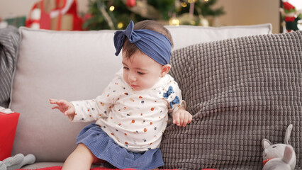 Poster - Adorable toddler sitting on sofa by christmas tree at home