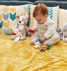 Adorable redhead toddler playing with car toy sitting on sofa at home