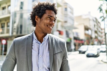 Wall Mural - Young african american businessman smiling happy standing at the city.