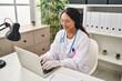 © Krakenimages.com - Young latin woman wearing doctor uniform using laptop working at clinic