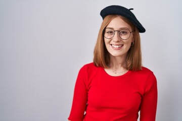 Wall Mural - Young redhead woman standing wearing glasses and beret with a happy and cool smile on face. lucky person.