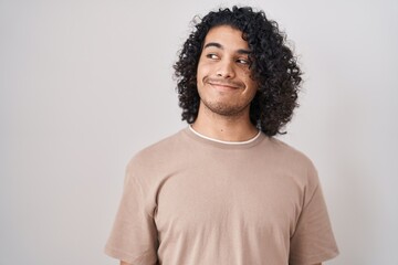 Poster - Hispanic man with curly hair standing over white background smiling looking to the side and staring away thinking.