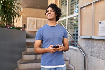 Sticker - Young hispanic man smiling confident using smartphone at street