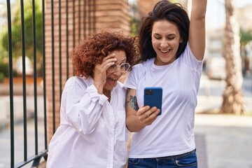 Poster - Two women mother and daughter standing together using smartphone at street