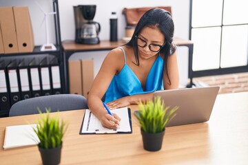 Sticker - Young beautiful latin woman business worker using laptop writing on document at office