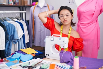 Poster - Hispanic young woman dressmaker designer using sewing machine confuse and wondering about question. uncertain with doubt, thinking with hand on head. pensive concept.