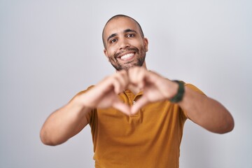 Canvas Print - Hispanic man with beard standing over white background smiling in love doing heart symbol shape with hands. romantic concept.