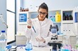 © Krakenimages.com - Young hispanic woman wearing scientist uniform using pipette working at laboratory