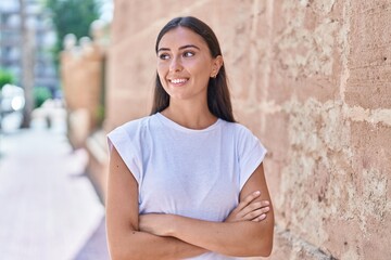 Young beautiful hispanic woman standing with arms crossed gesture at street