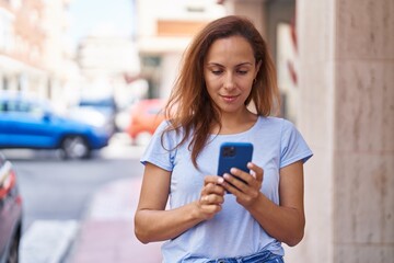 Poster - Young woman smiling confident using smartphone at street