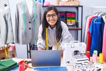 Sticker - Young beautiful hispanic woman tailor smiling confident using laptop at clothing factory