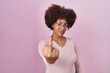 Young african american woman standing over pink background showing middle finger, impolite and rude fuck off expression