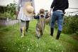 © Caia Image - Family holding hands and walking in garden grass