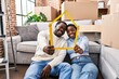 © Krakenimages.com - Man and woman couple holding house project sitting on floor at new home
