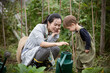 © Caia Image - Mother and toddler son with watering can in garden